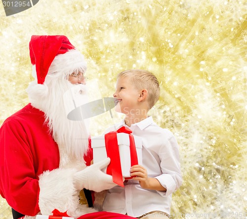 Image of smiling little boy with santa claus and gifts