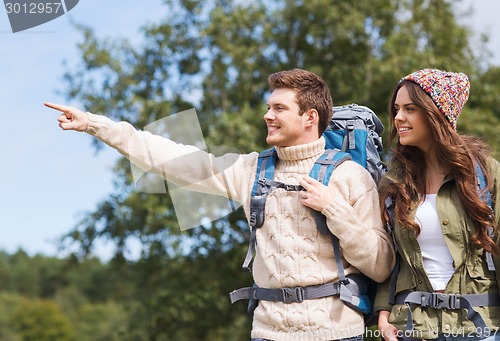 Image of smiling hikers with backpacks pointing finger