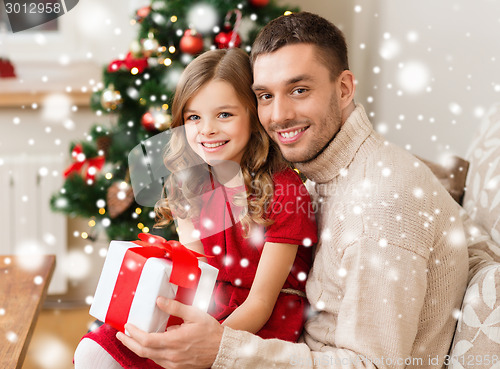 Image of smiling father and daughter with gift box at home