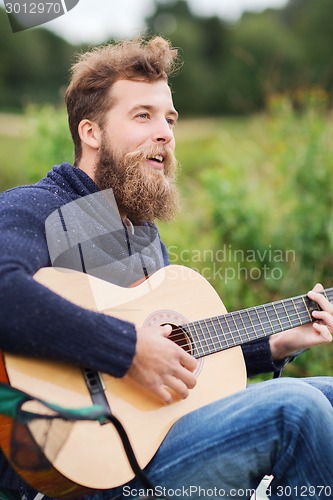 Image of smiling man playing guitar in camping