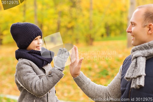 Image of happy father and son making high five in park