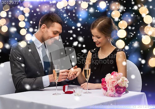 Image of smiling couple with red gift box at restaurant