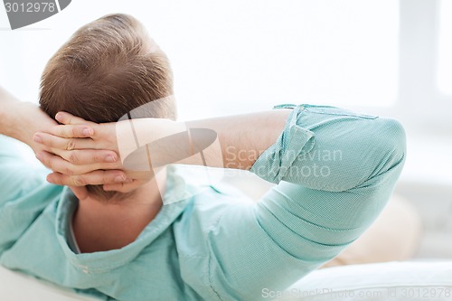 Image of man lying or sitting on sofa at home from back