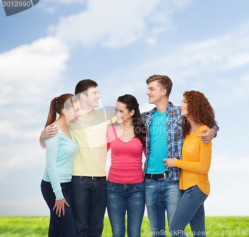 Image of group of smiling teenagers over blue sky and grass