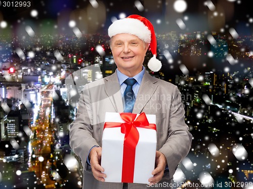 Image of smiling man in suit and santa helper hat with gift