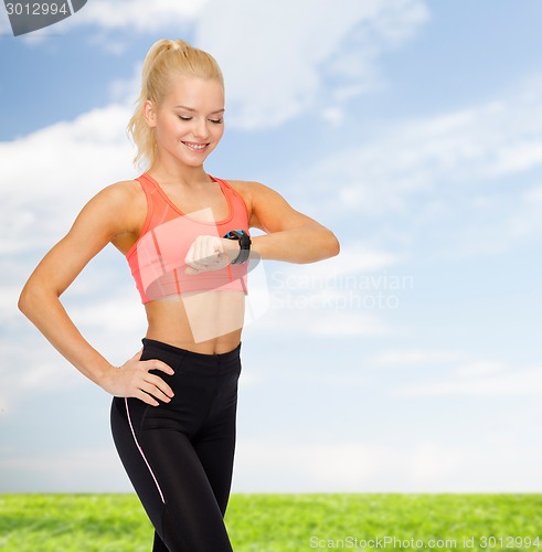 Image of smiling woman with heart rate monitor on hand