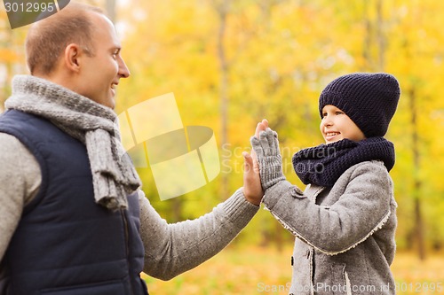 Image of happy father and son making high five in park