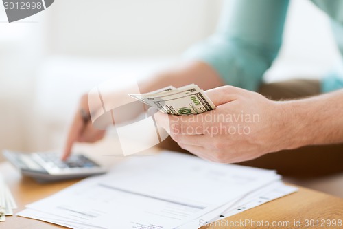 Image of close up of man counting money and making notes