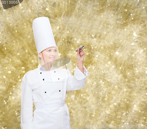 Image of smiling female chef writing something on air