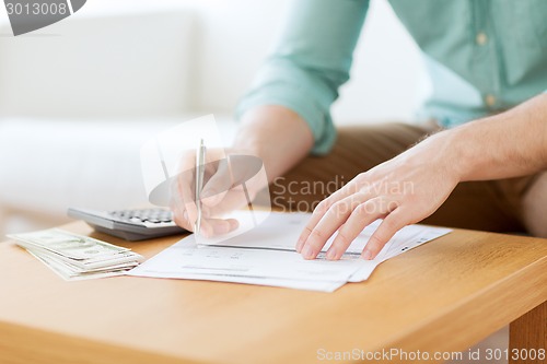 Image of close up of man counting money and making notes