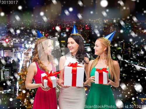 Image of smiling women in party caps with gift boxes