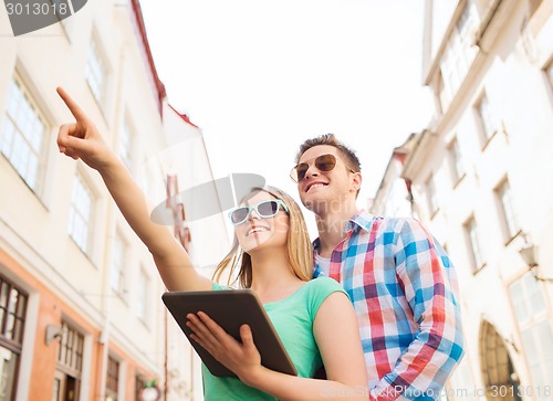 Image of smiling couple with tablet pc in city
