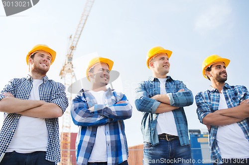 Image of group of smiling builders in hardhats outdoors