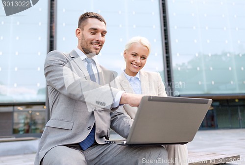 Image of smiling businesspeople with laptop outdoors