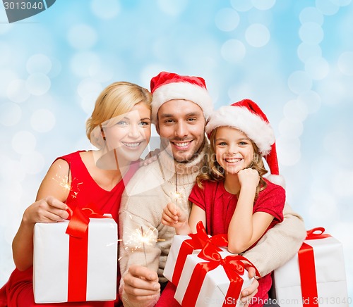 Image of happy family in santa helper hats with gift boxes