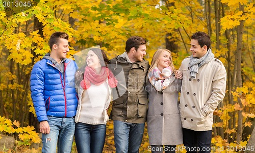 Image of group of smiling men and women in autumn park