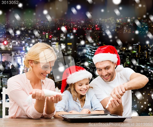 Image of happy family in santa helper hats cooking