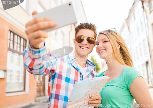 Image of smiling couple with smartphone in city