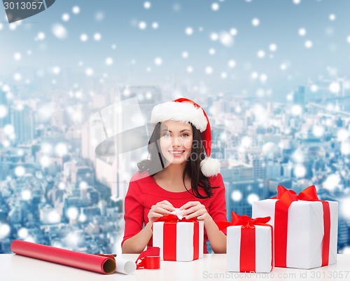 Image of smiling woman in santa helper hats packing gifts