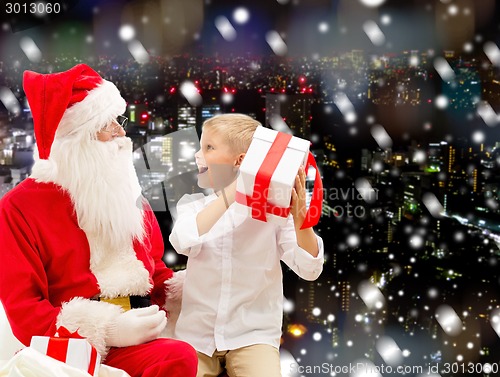 Image of smiling little boy with santa claus and gifts