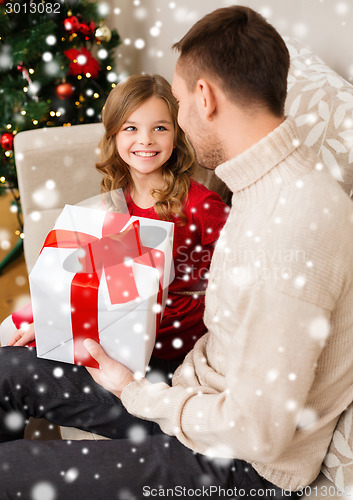 Image of smiling father and daughter with gift box at home