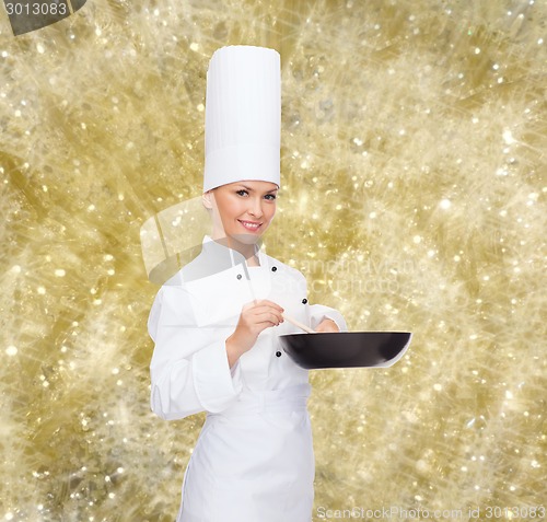 Image of smiling female chef with pan and spoon