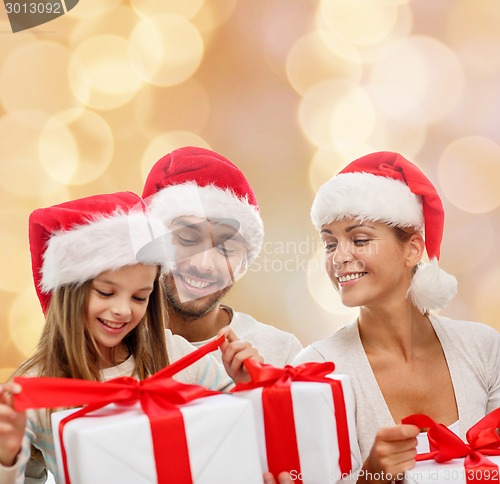 Image of happy family in santa helper hats with gift boxes