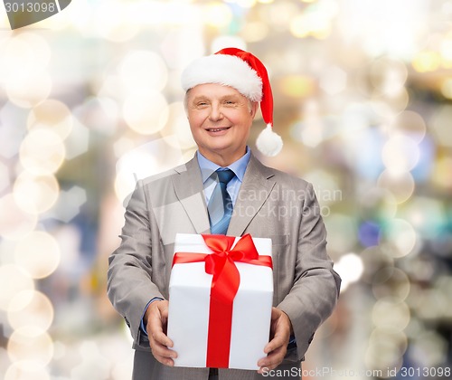 Image of smiling man in suit and santa helper hat with gift