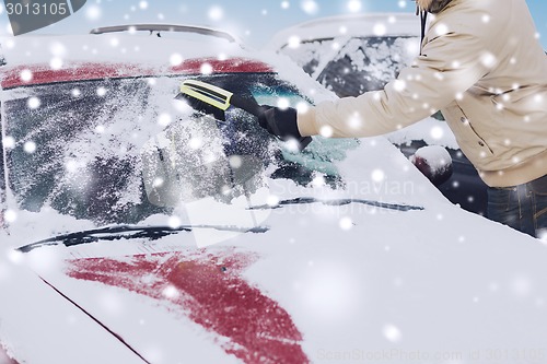 Image of closeup of man cleaning snow from car