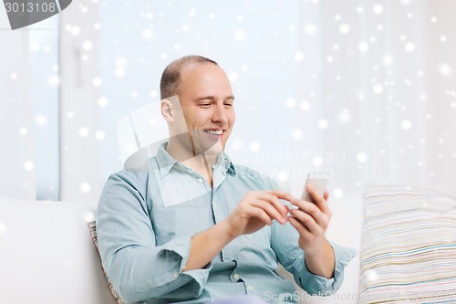 Image of smiling man with smartphone at home