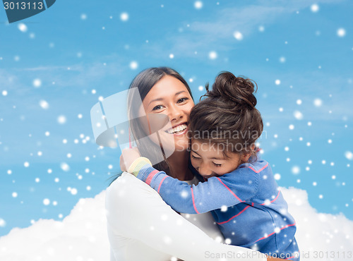 Image of smiling little girl and mother hugging indoors