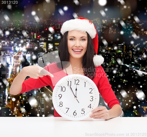 Image of smiling woman in santa helper hat with clock