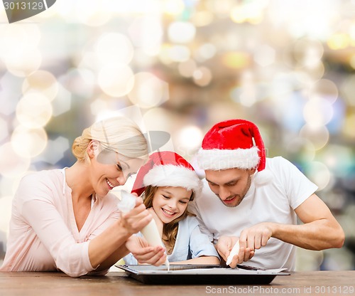 Image of happy family in santa helper hats cooking