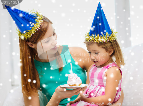 Image of mother and daughter in party hats with cake