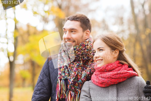 Image of smiling couple hugging on bridge in autumn park