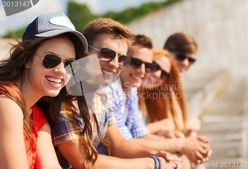 Image of close up of smiling friends sitting on city street