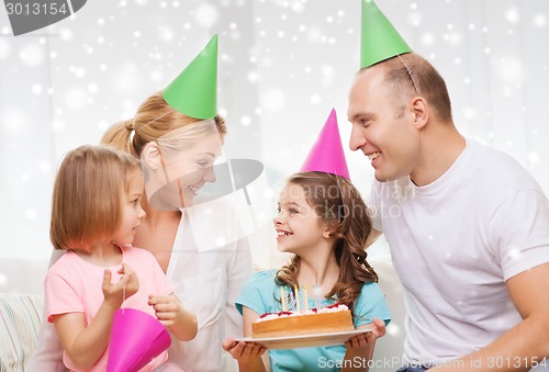 Image of happy family with two kids in party hats at home