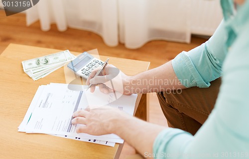 Image of close up of man counting money and making notes