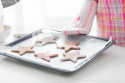 Image of close up of woman with cookies on oven tray