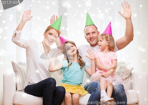 Image of happy family with two kids in party hats at home
