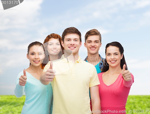 Image of group of smiling teenagers over blue sky and grass