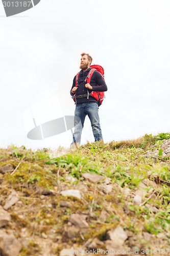 Image of tourist with beard and backpack raising hands