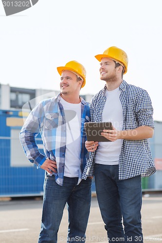 Image of smiling builders with tablet pc outdoors