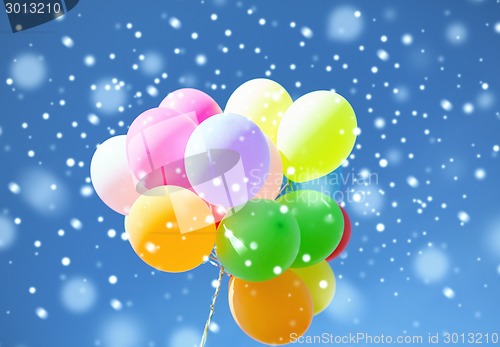 Image of lots of colorful balloons in sky with snowflakes