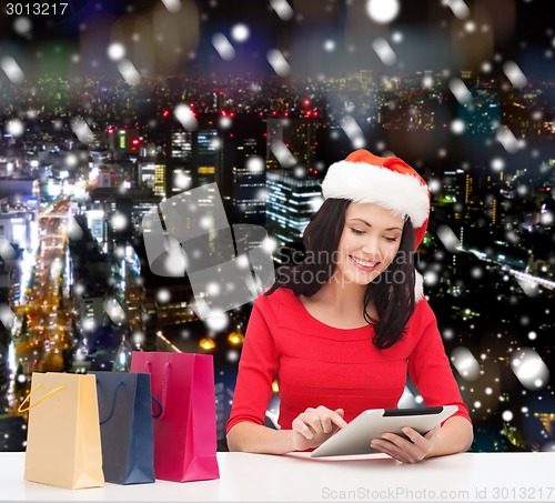 Image of smiling woman with shopping bags and tablet pc