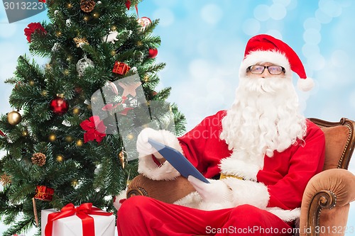 Image of man in costume of santa claus with tablet pc