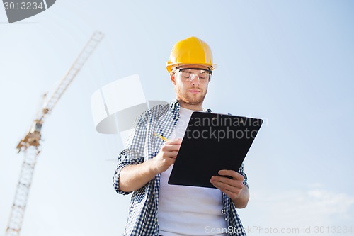 Image of builder in hardhat with clipboard outdoors