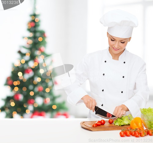 Image of smiling female chef chopping vegetables