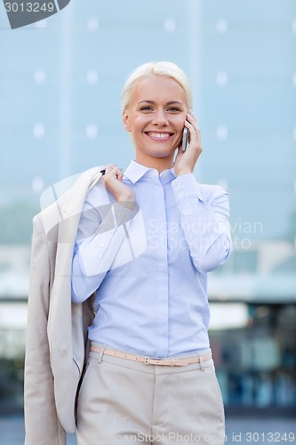 Image of smiling businesswoman with smartphone outdoors