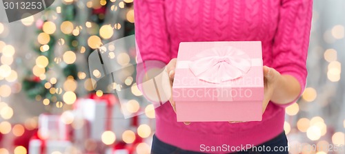 Image of close up of woman in pink sweater holding gift box